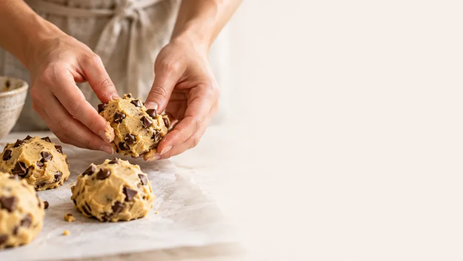 Hands shaping chocolate chip cookie dough